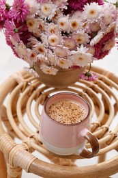 Photo of Cup of fresh coffee and beautiful bouquet on wooden stand. Good morning