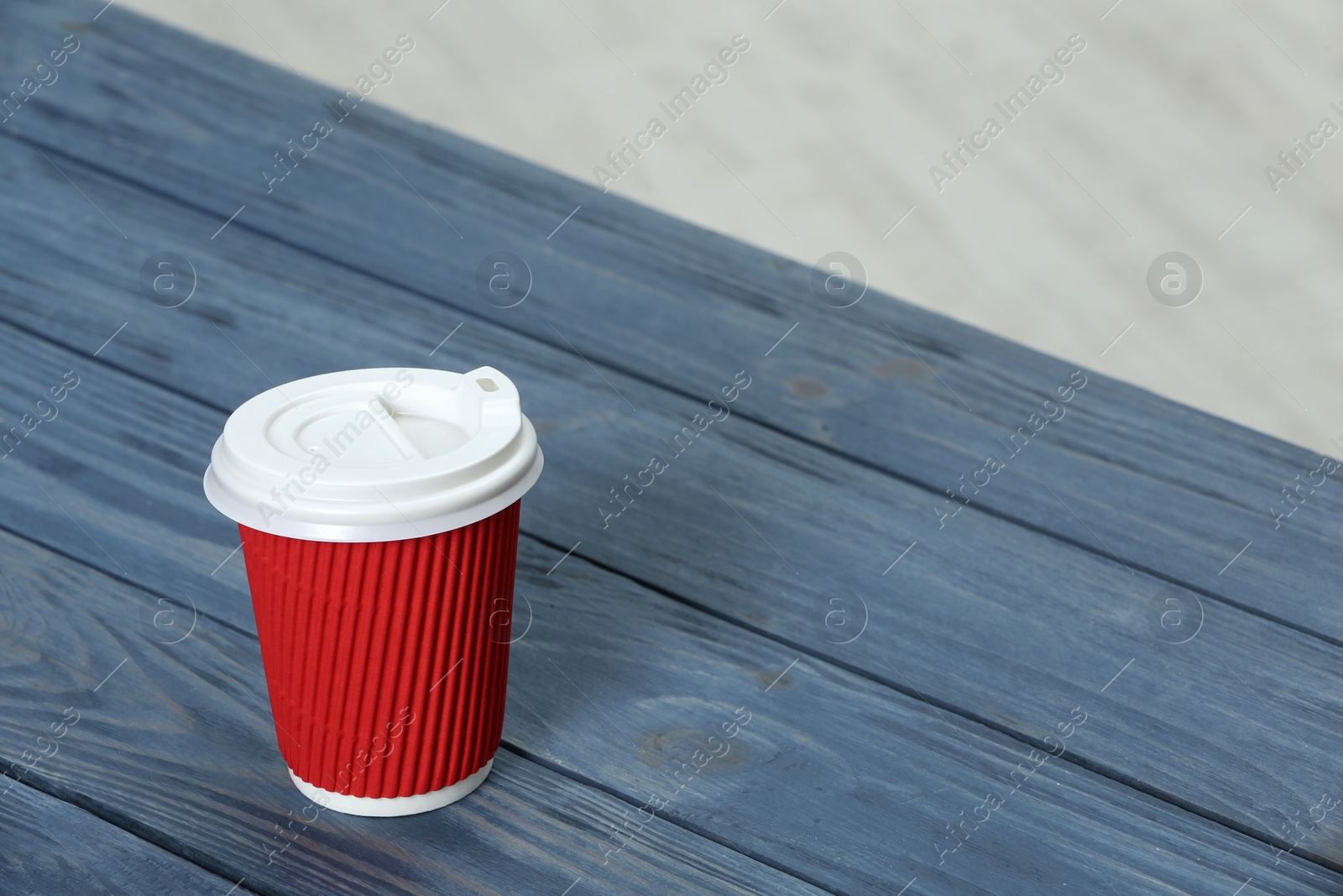 Photo of Cardboard coffee cup with lid on wooden table. Space for text