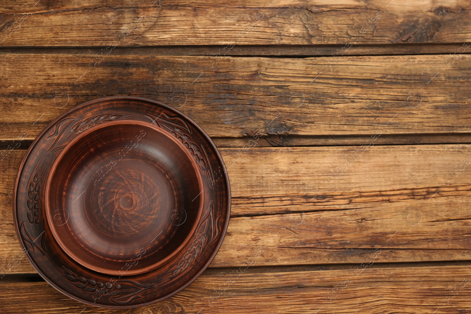 Photo of Clay plate and bowl on wooden table, top view with space for text. Handmade utensils