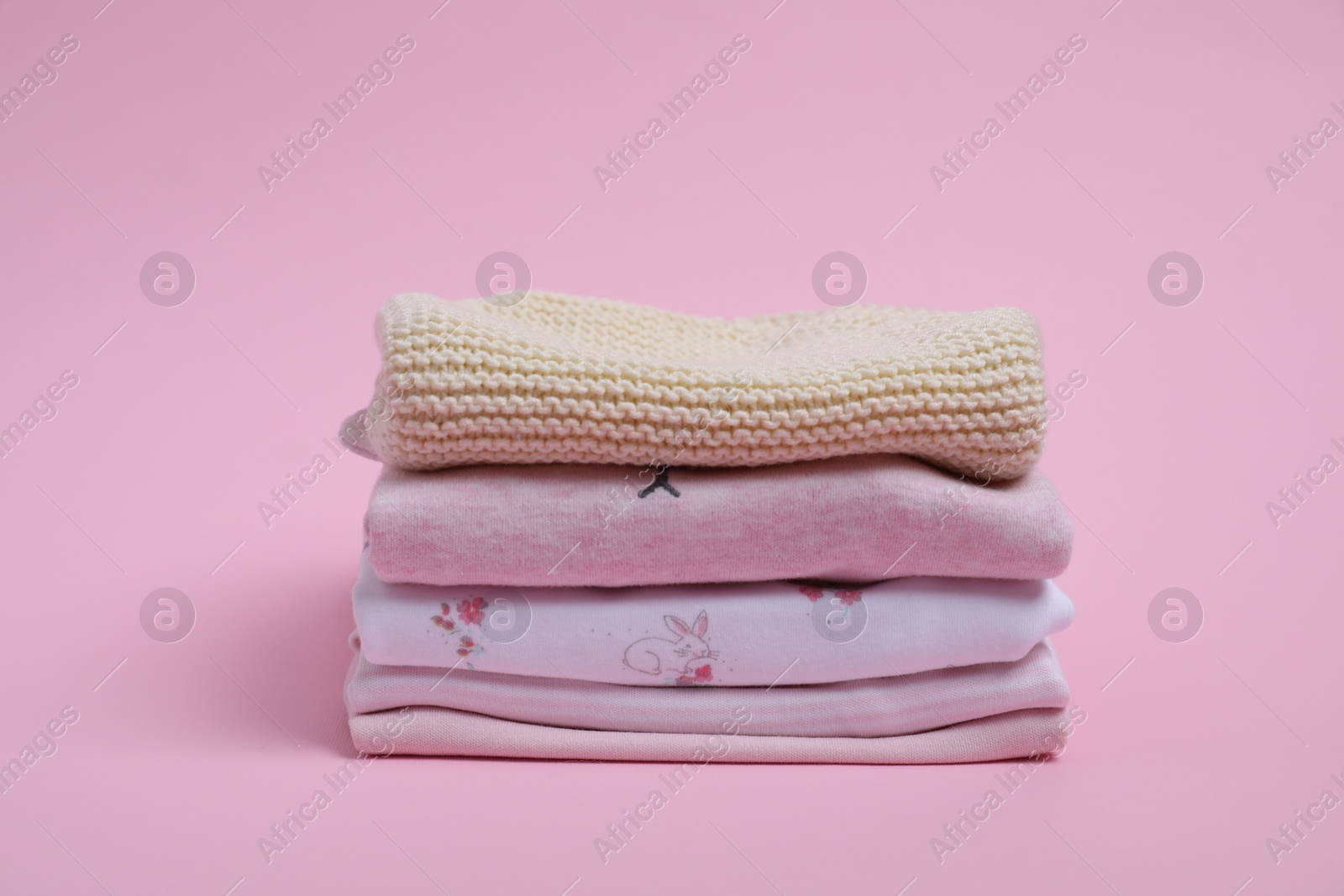 Photo of Stack of clean baby clothes on pink background