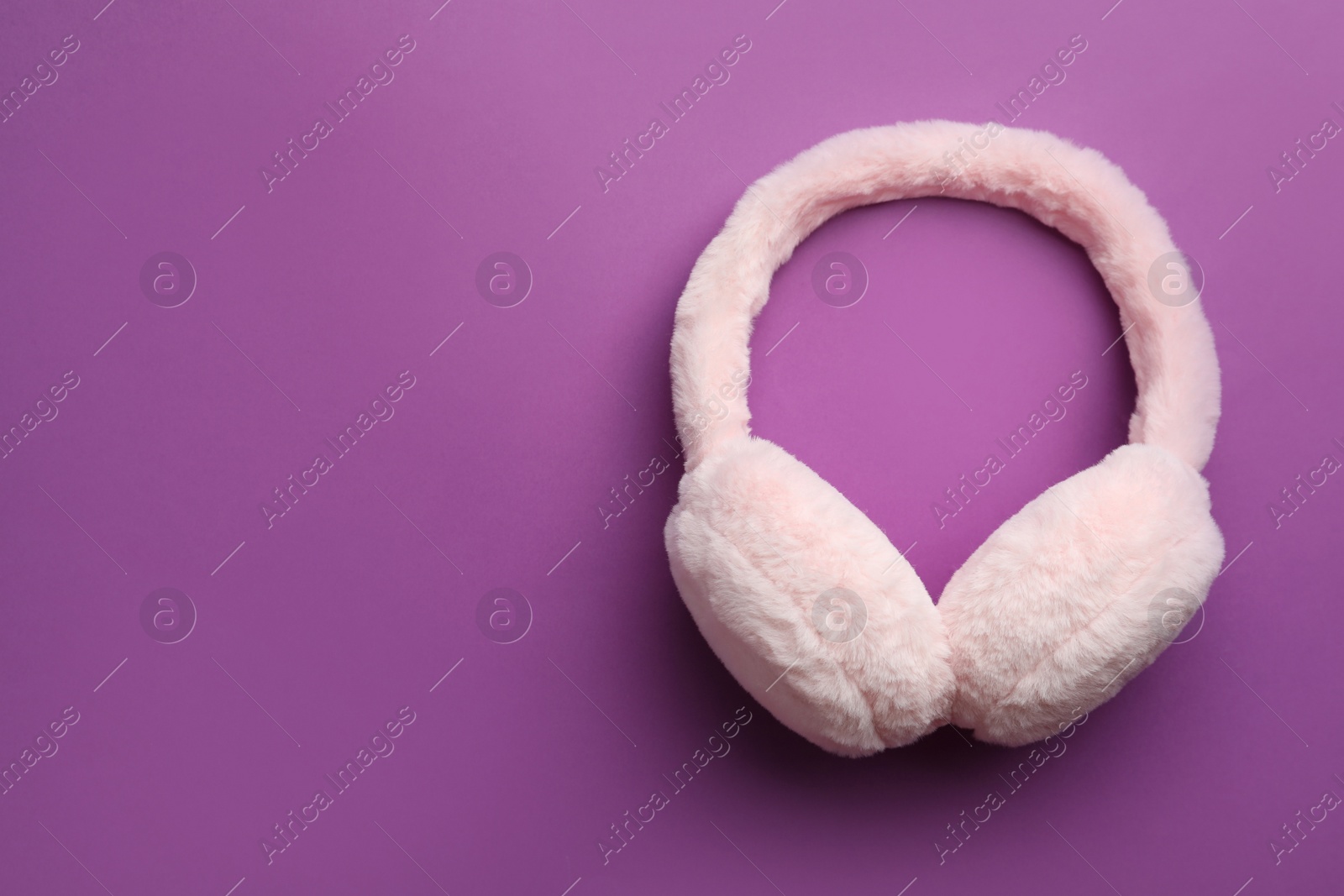 Photo of Stylish winter earmuffs on purple background, top view. Space for text