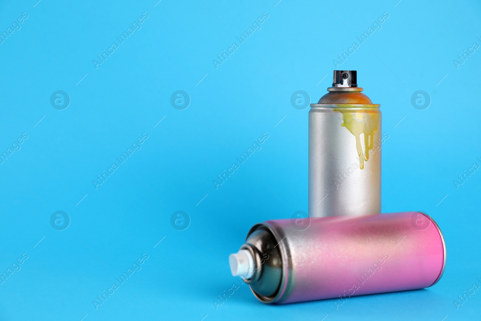 Photo of Used cans of spray paints on light blue background. Space for text