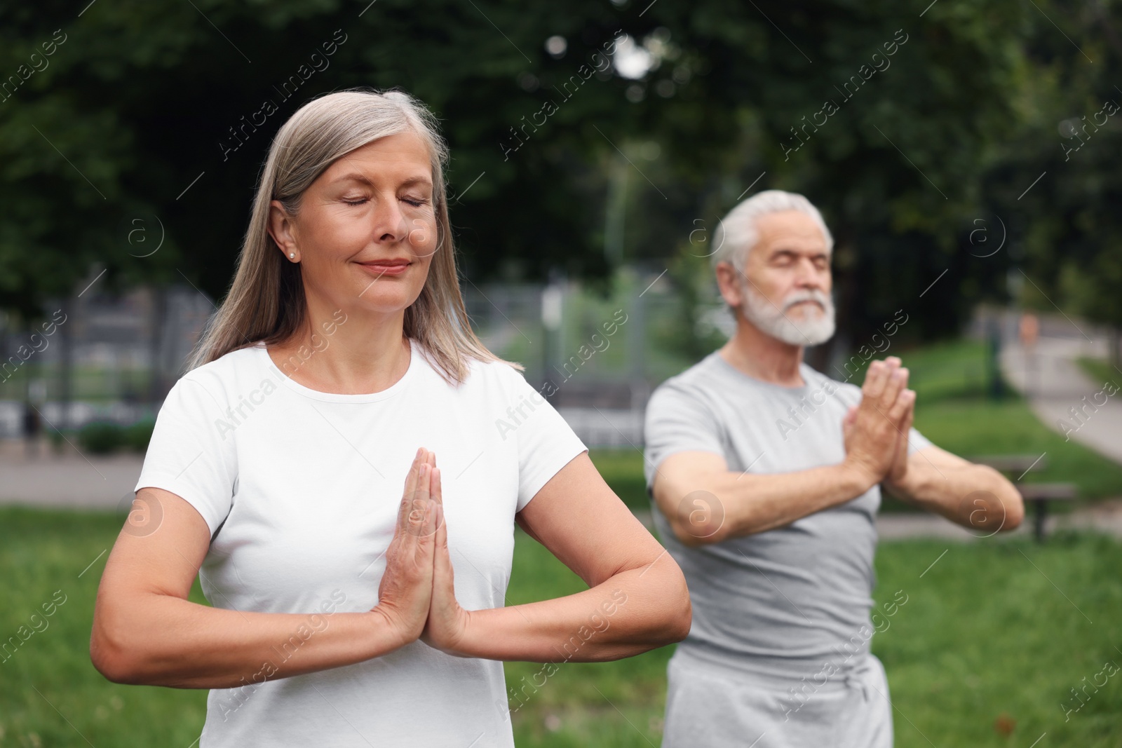 Photo of Senior couple practicing yoga in park, selective focus