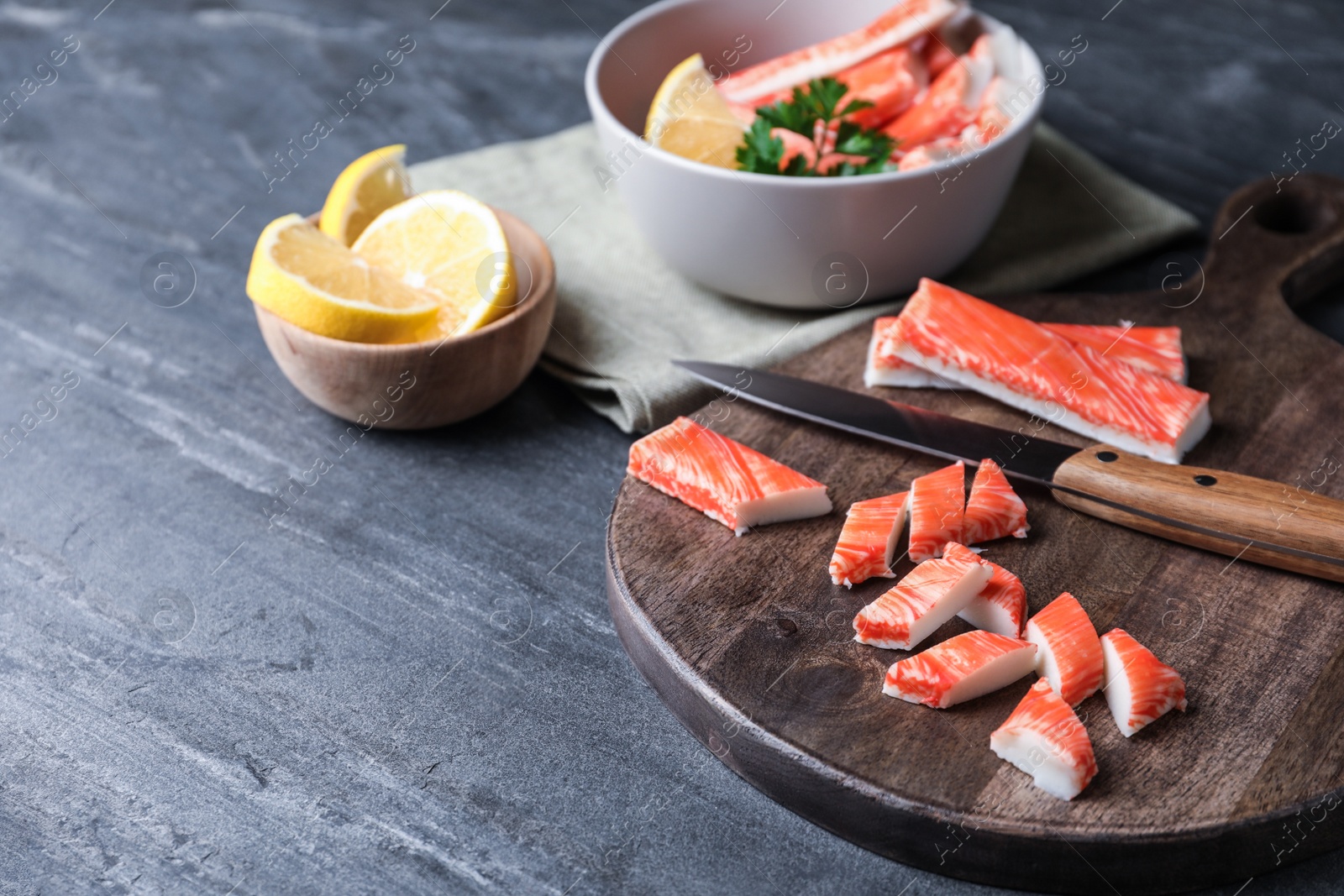 Photo of Fresh crab sticks, knife and lemon on grey table