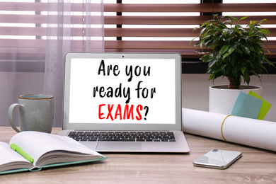 Image of Laptop with phrase ARE YOU READY FOR EXAMS on wooden table in office