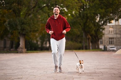 Man running with adorable Jack Russell Terrier on city street. Dog walking