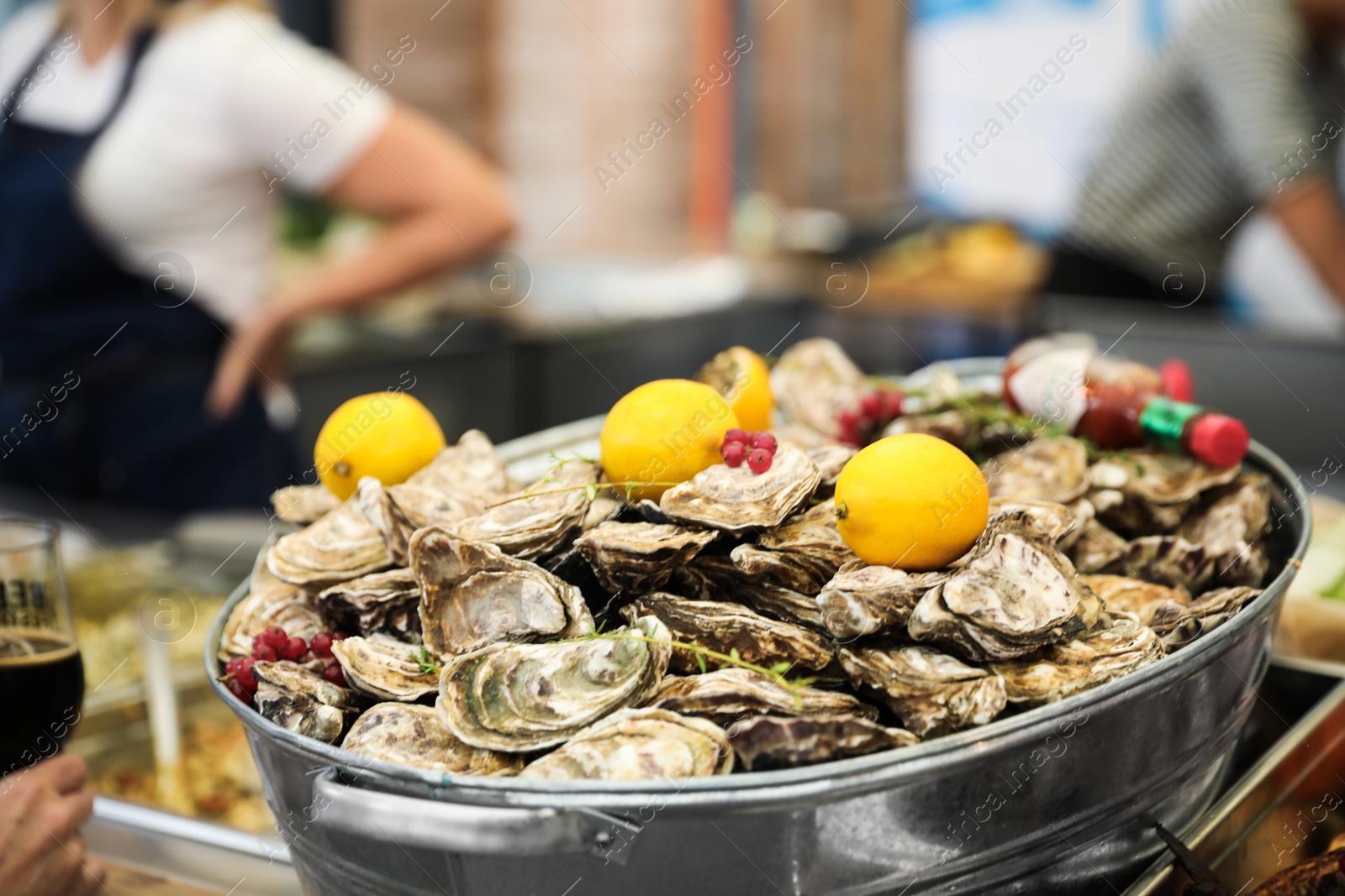 Photo of Fresh oysters served with lemons in dish, closeup