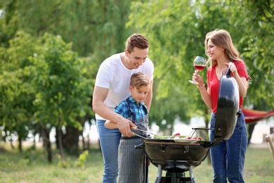 Happy family having barbecue with modern grill outdoors