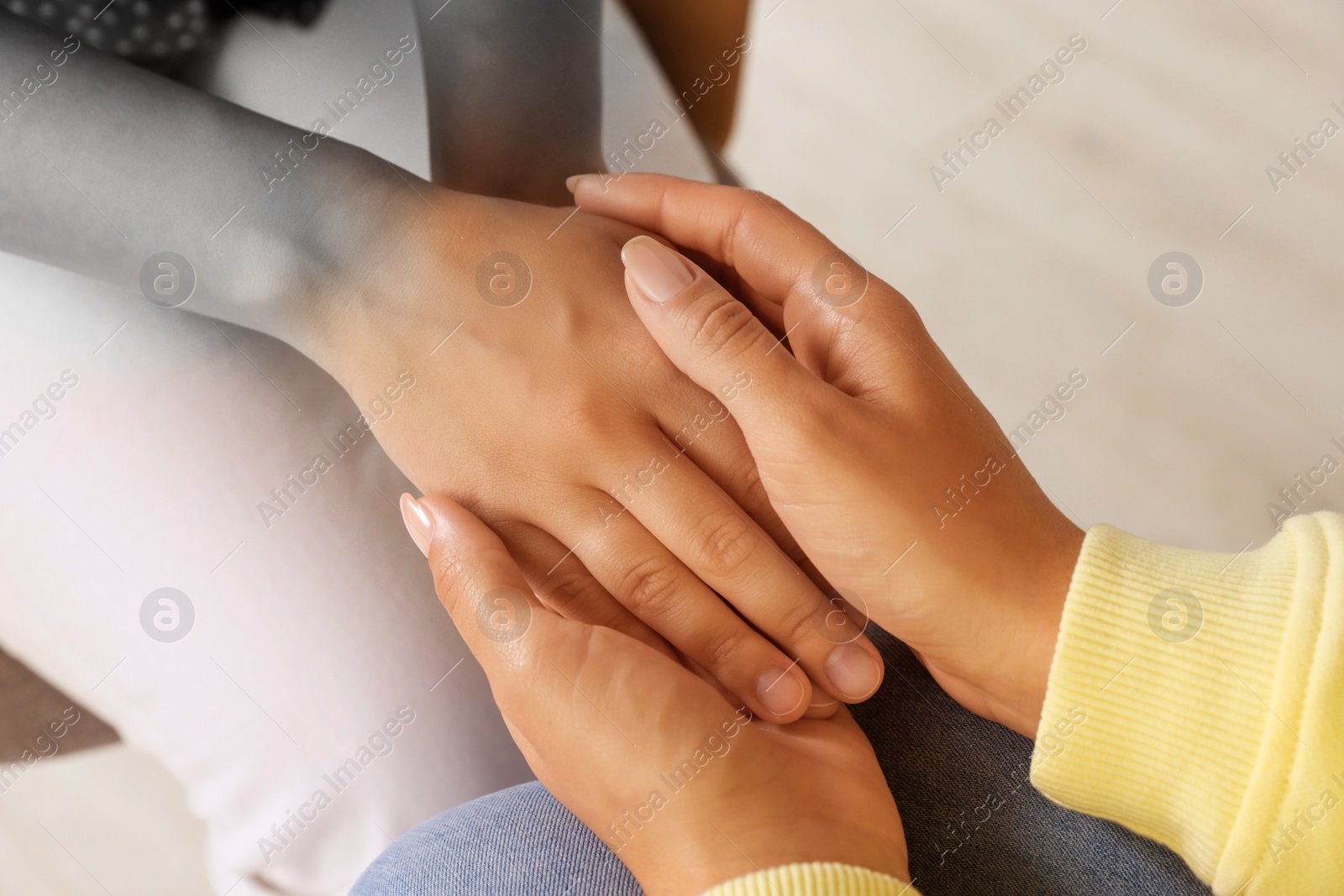 Image of Empathy. Women holding hands indoors, closeup. Transition from black and white to color on photo as symbol of emotional support