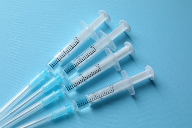 Disposable syringes with needles and medicine on light blue background, flat lay