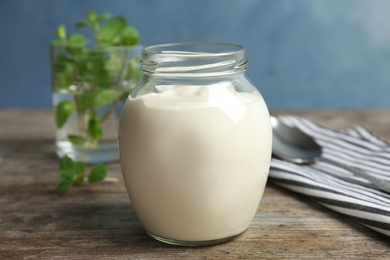 Photo of Jar with yummy yogurt on wooden table