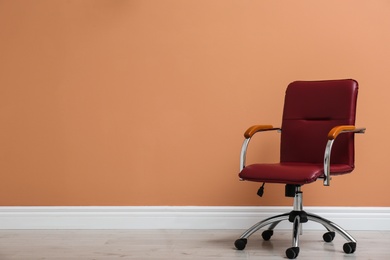 Modern office chair near orange coral wall indoors. Space for text