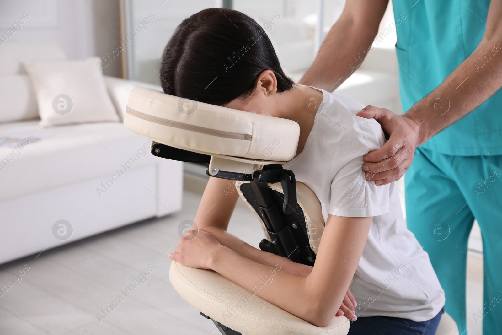 Photo of Woman receiving massage in modern chair indoors