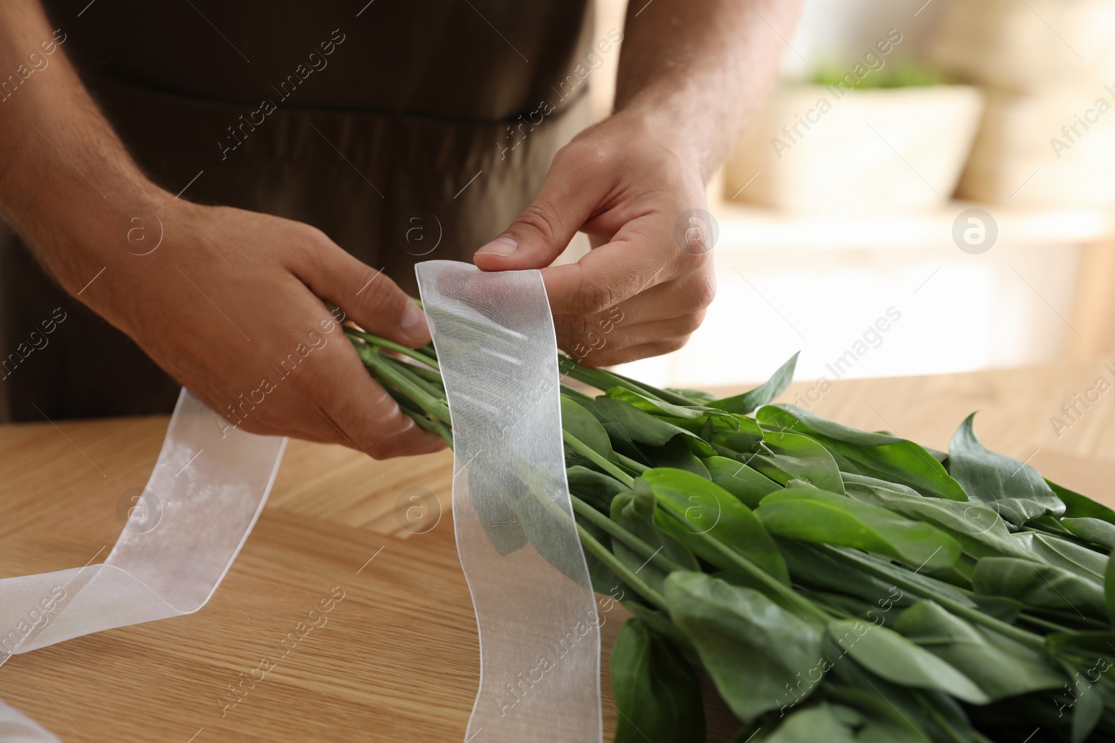 Photo of Florist making beautiful bouquet at table in workshop, closeup