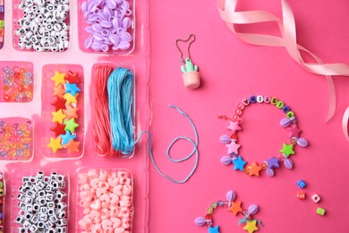 Photo of Handmade jewelry kit for kids. Colorful beads, ribbon and bracelets on bright pink background, flat lay