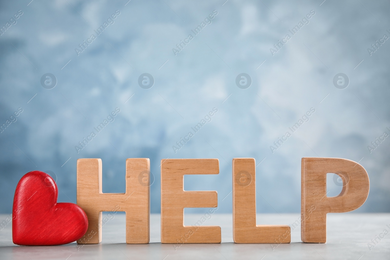 Photo of Word Help made of letters and red heart on table