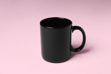 Photo of One black ceramic mug on pink background
