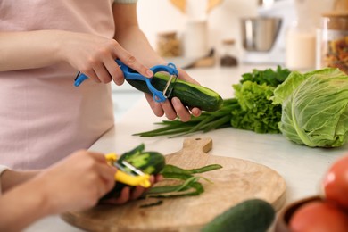 Mother and daughter peeling vegetables at kitchen counter, closeup