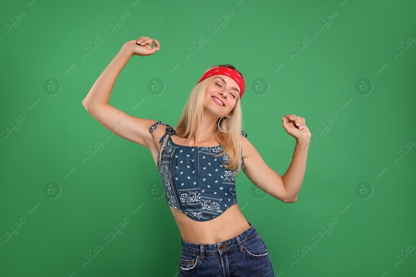 Photo of Portrait of happy hippie woman dancing on green background