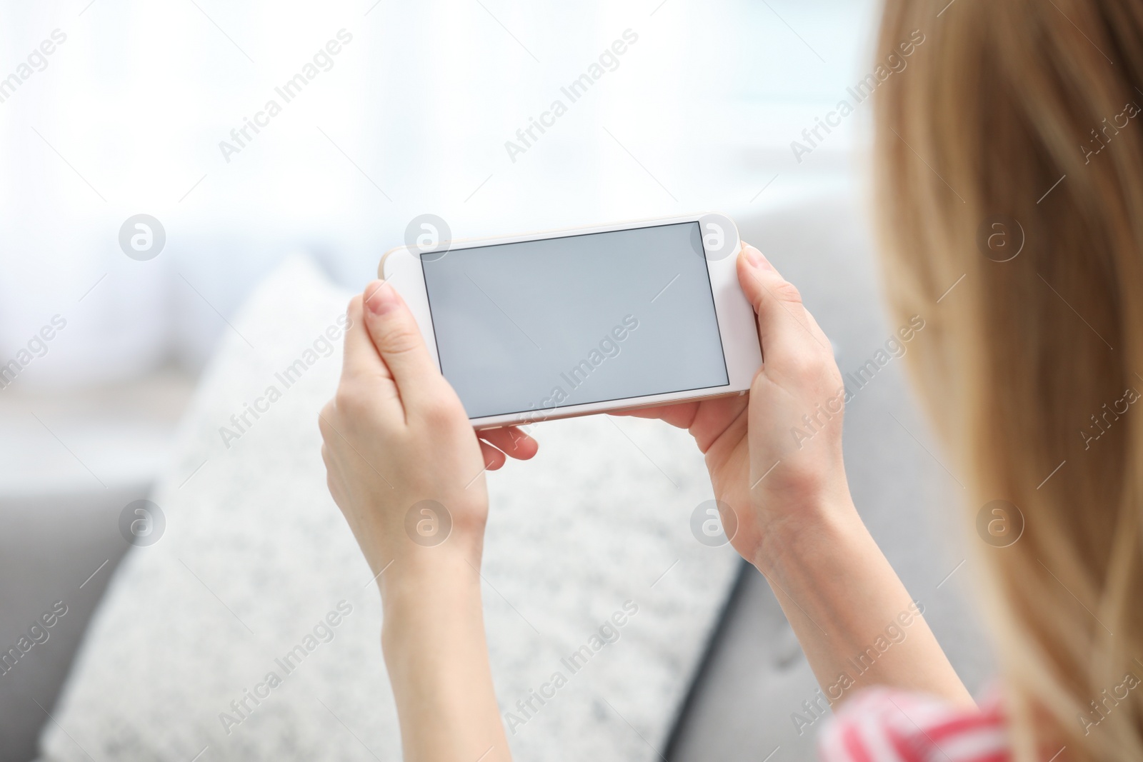 Photo of Young woman using video chat on smartphone in living room, closeup. Space for design