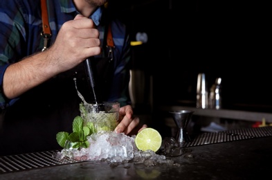 Barman making Mojito cocktail at counter in pub, closeup. Space for text