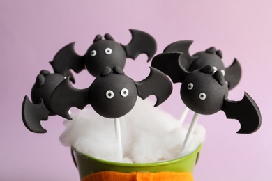 Photo of Delicious bat shaped cake pops on pink background, closeup. Halloween treat