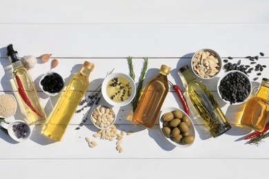 Flat lay composition with different cooking oils and ingredients on white wooden table