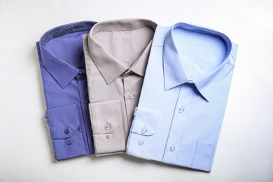 Photo of Stylish shirts on light table, flat lay. Dry-cleaning service