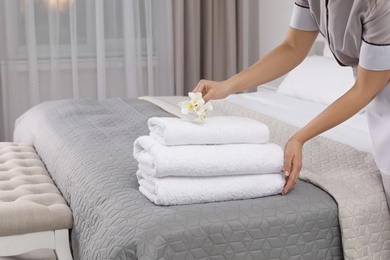 Maid putting flowers on fresh towels in hotel room, closeup