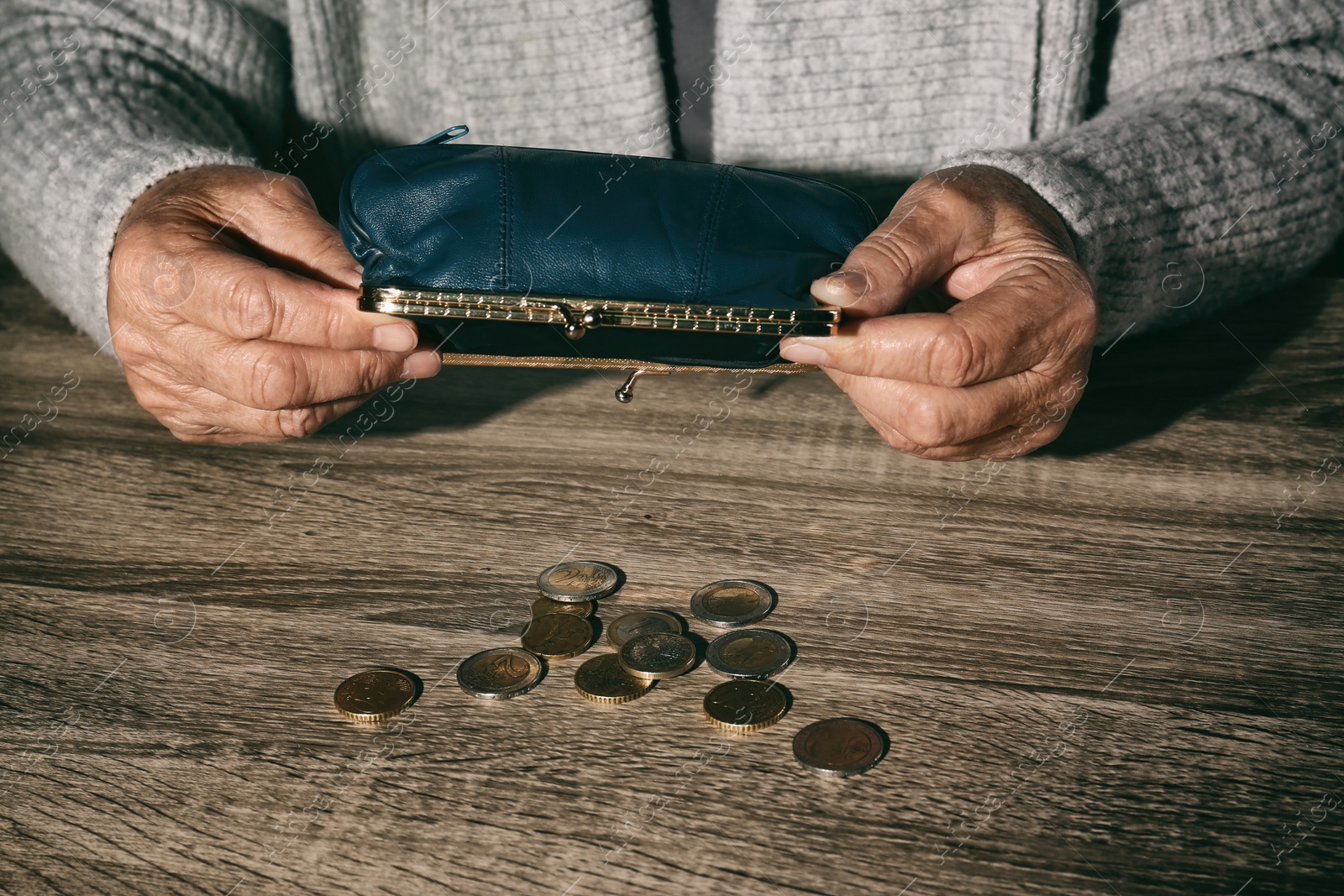 Photo of Poor senior woman with empty wallet and coins at table, closeup
