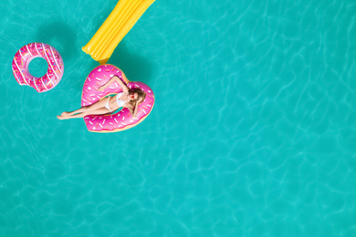 Image of Happy woman with inflatable mattress and rings in swimming pool, top view. Summer vacation