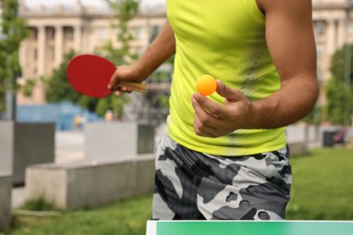 Man playing ping pong outdoors on summer day, closeup
