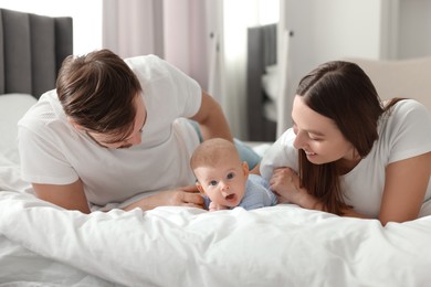 Happy family. Parents with their cute baby on bed indoors