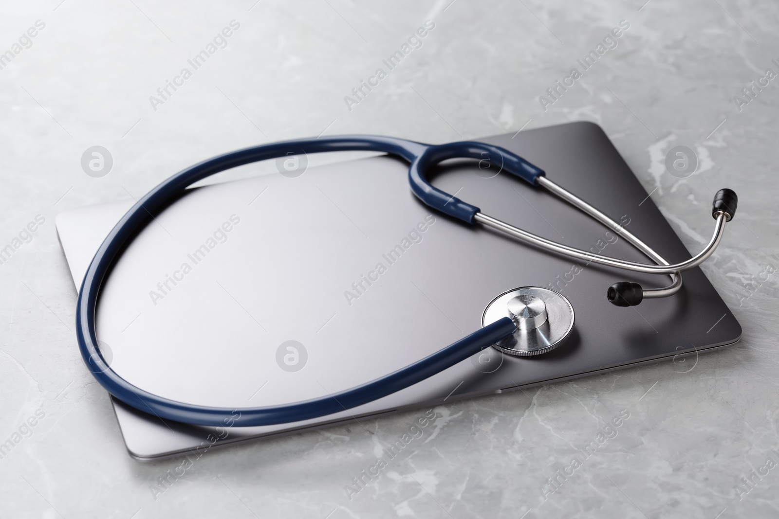 Photo of Modern laptop and stethoscope on grey table