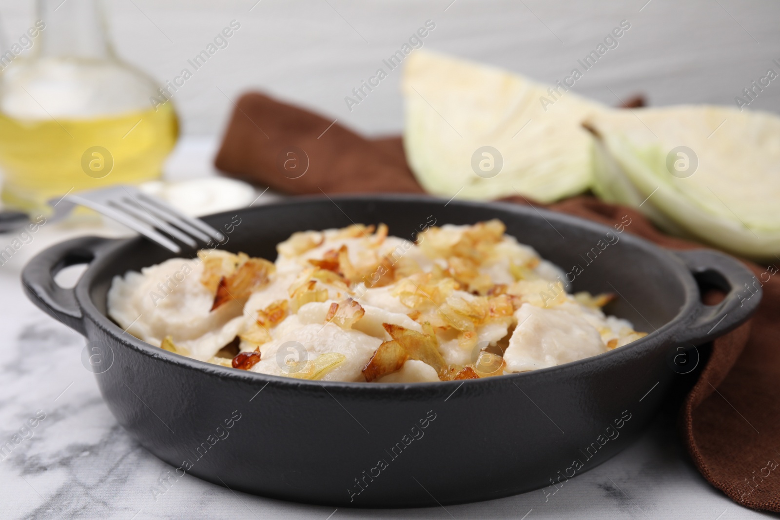 Photo of Cooked dumplings (varenyky) with tasty filling and fried onions on white marble table, closeup