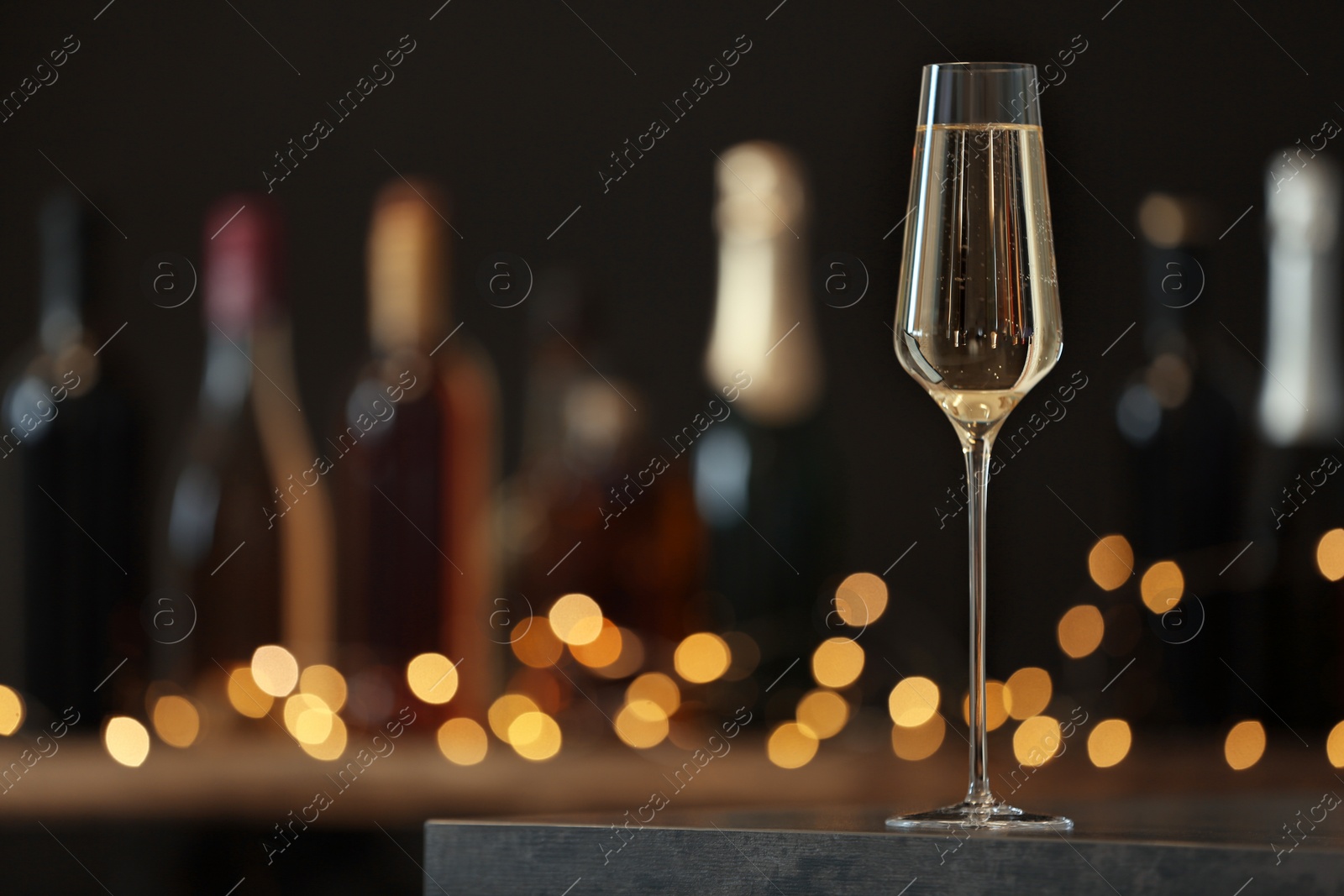 Photo of Glass of champagne on table against blurred background. Space for text