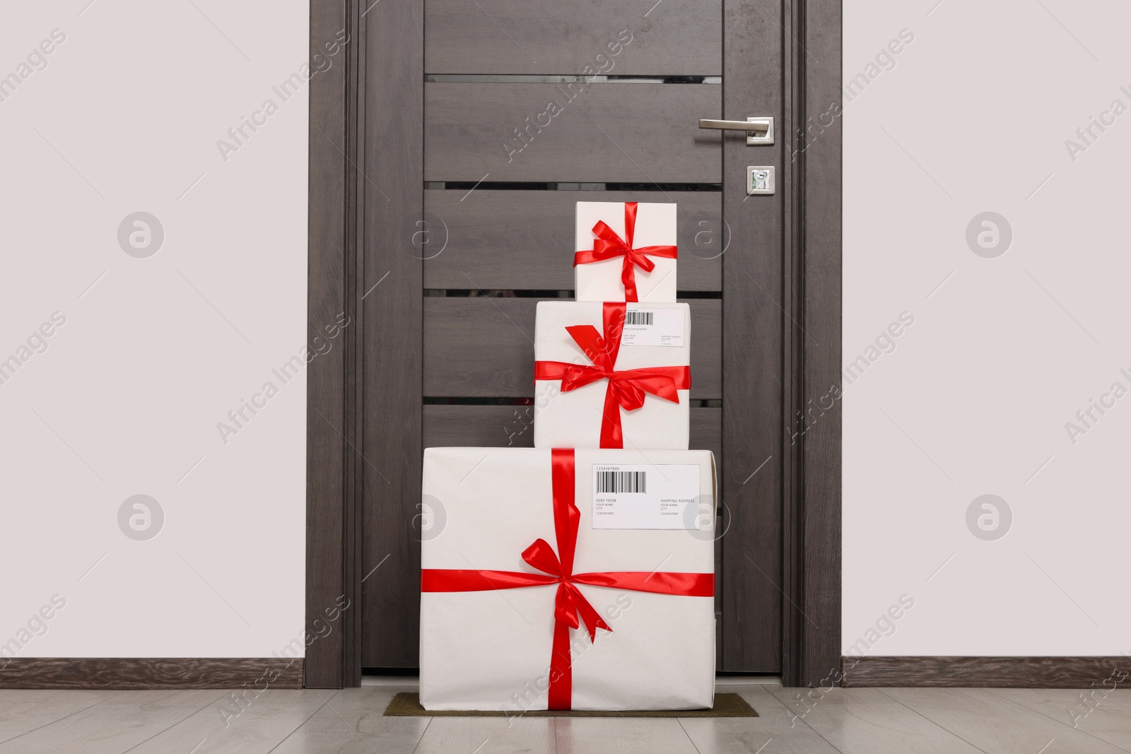 Photo of Christmas gift boxes on floor near door. Sending present by mail