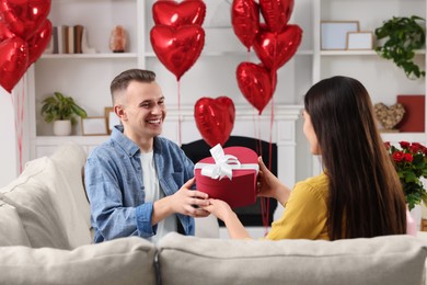 Photo of Man receiving gift box from his girlfriend at home. Valentine's day celebration