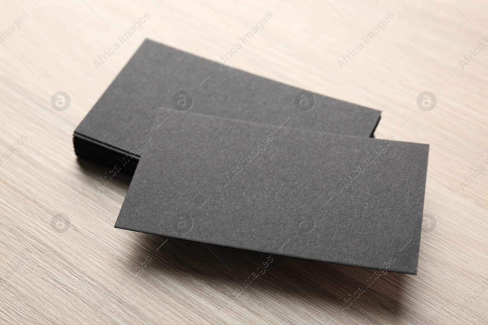 Photo of Blank black business cards on wooden table, closeup. Mockup for design