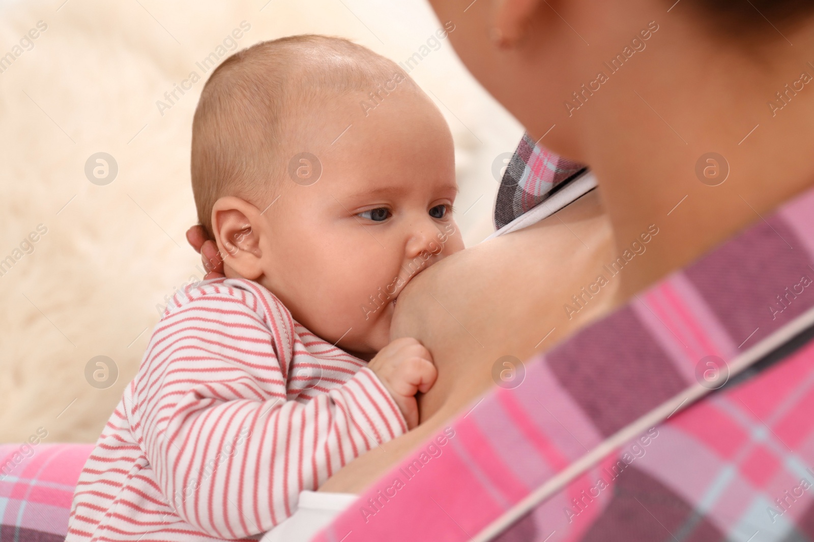 Photo of Young woman breastfeeding her little baby at home, closeup