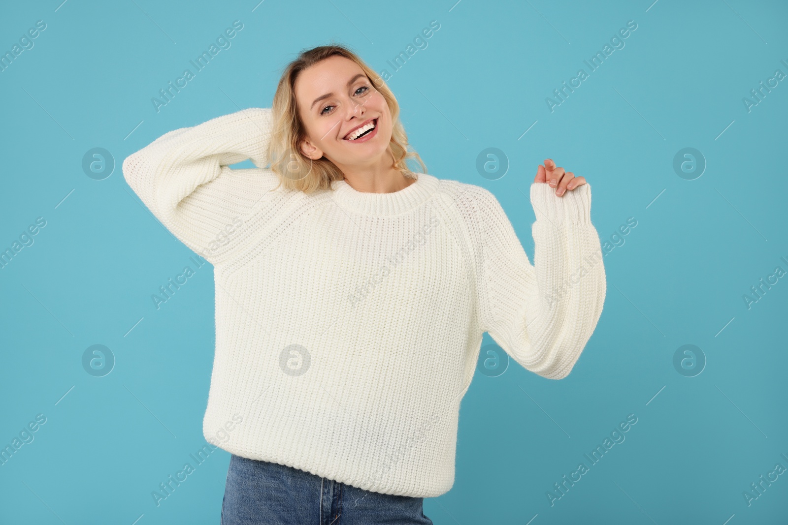 Photo of Happy woman in stylish warm sweater on light blue background