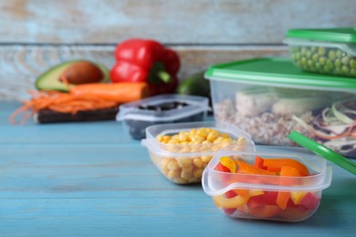 Set of plastic containers with fresh food on light blue wooden table, space for text