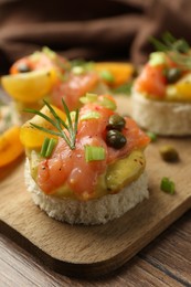 Tasty canapes with salmon served on wooden table, closeup