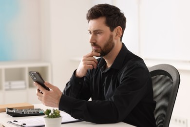 Photo of Handsome man using smartphone at table in office