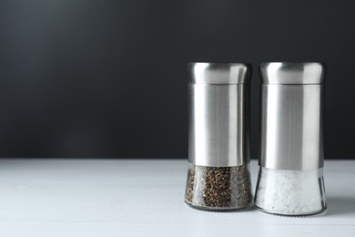 Photo of Salt and pepper shakers on white table, space for text