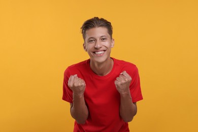 Photo of Happy sports fan celebrating on orange background