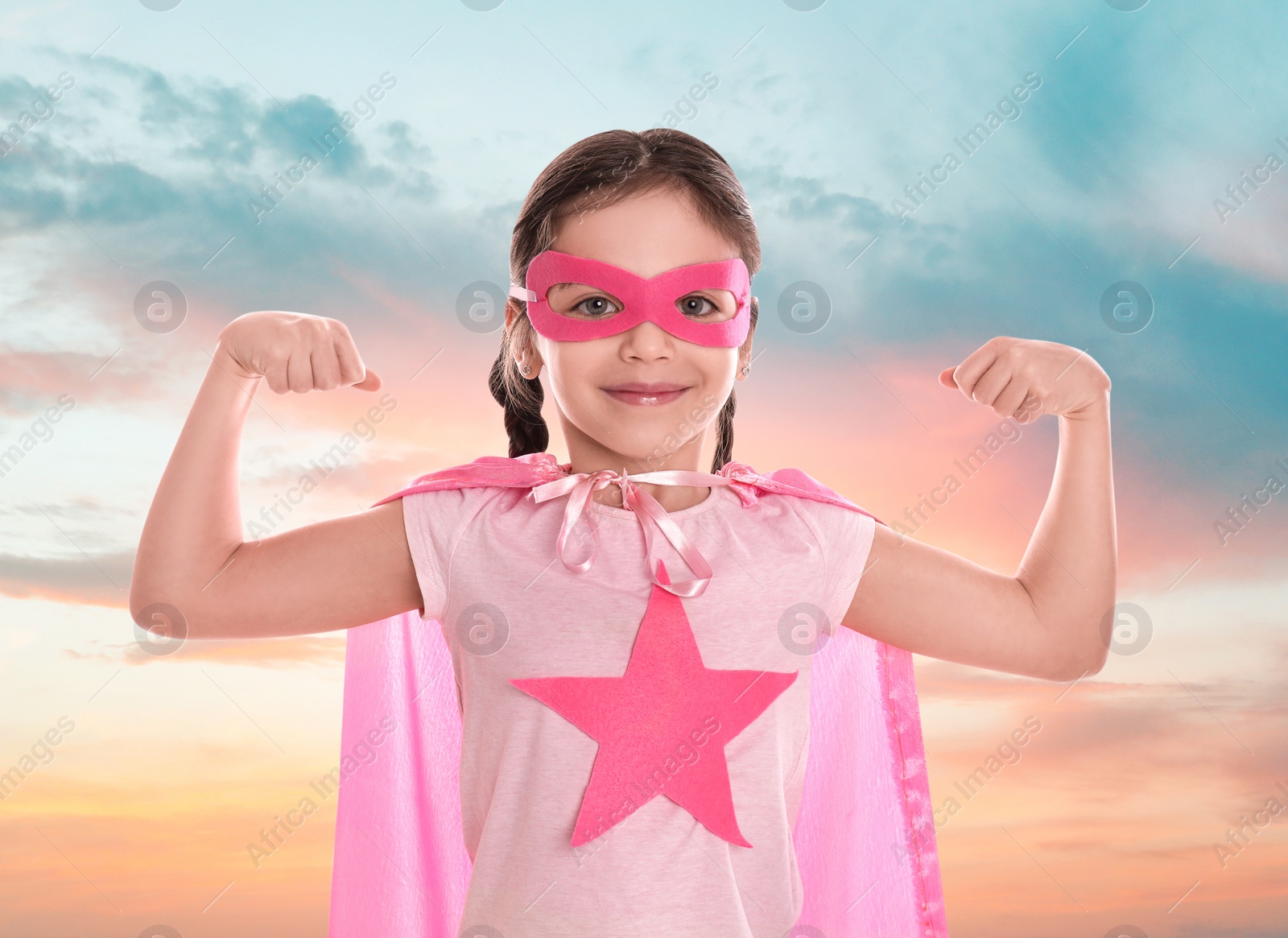 Image of Cute little girl in superhero costume against cloudy sky