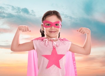 Image of Cute little girl in superhero costume against cloudy sky
