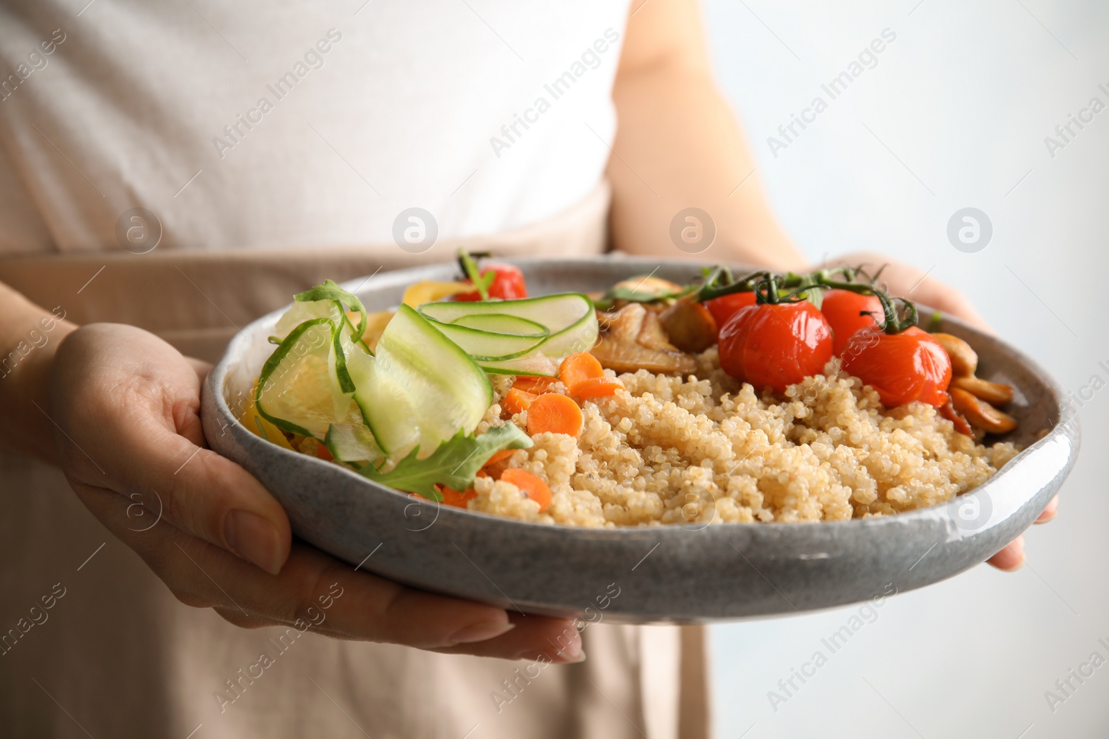 Photo of Woman holding plate with healthy quinoa salad and vegetables, closeup