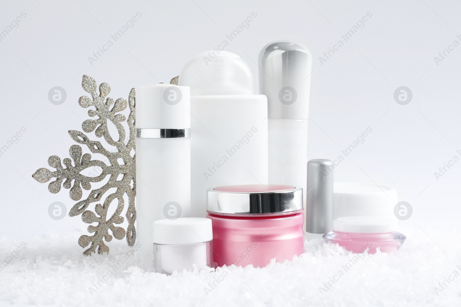 Photo of Set of cosmetic products and decorative snow on white background. Winter care